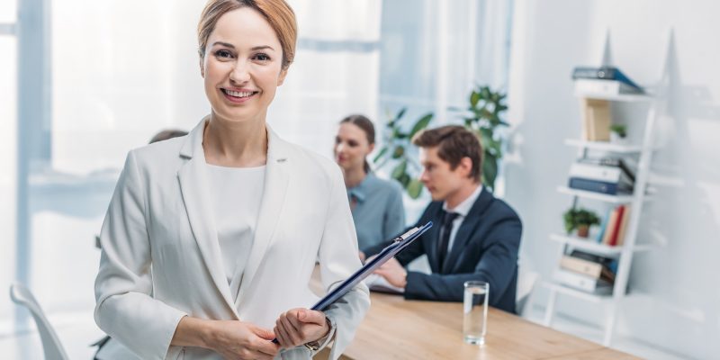 selective-focus-of-cheerful-recruiter-standing-with-clipboard-near-coworkers-q4vhguznfuxsbaju44pu2szhgrfac5e07m26x4n9gg